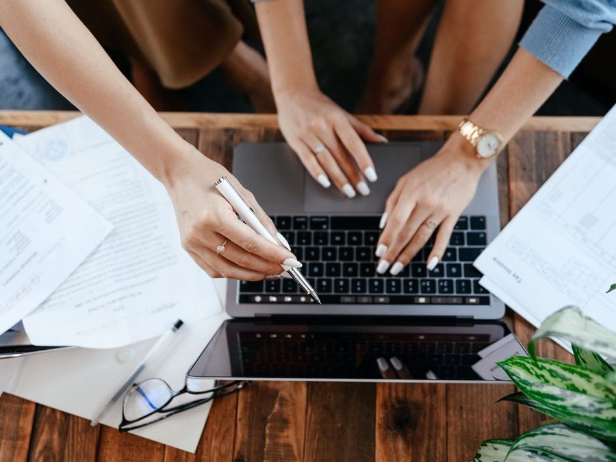 Ręce przy laptopie wśród dokumentów na biurku